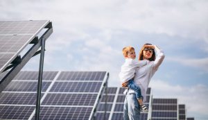 Donna con in braccio un bambino vicino ad un impianto fotovoltaico